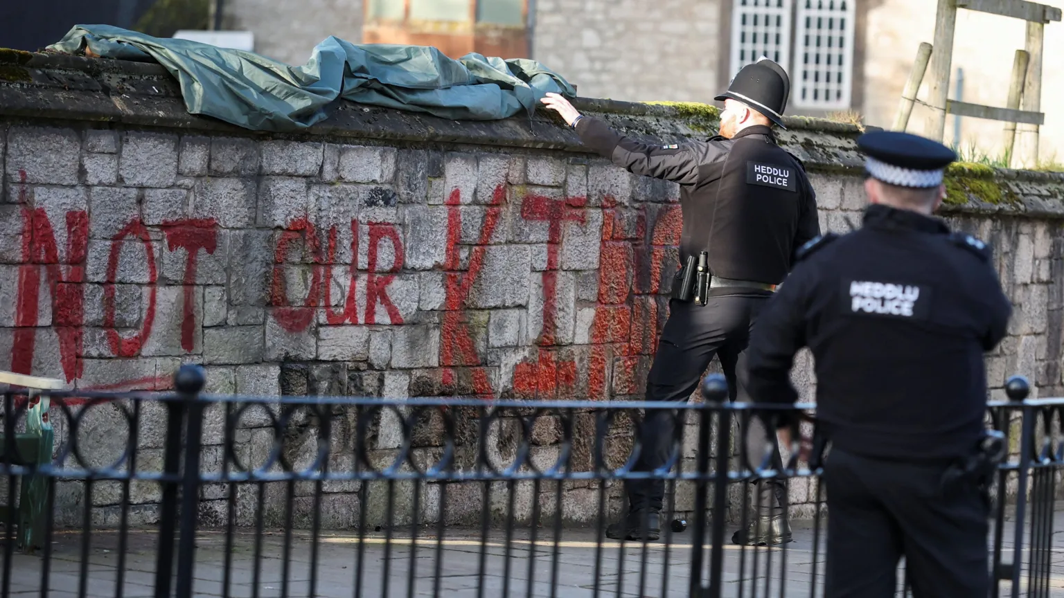  A police officer pulls a tarp over the words 