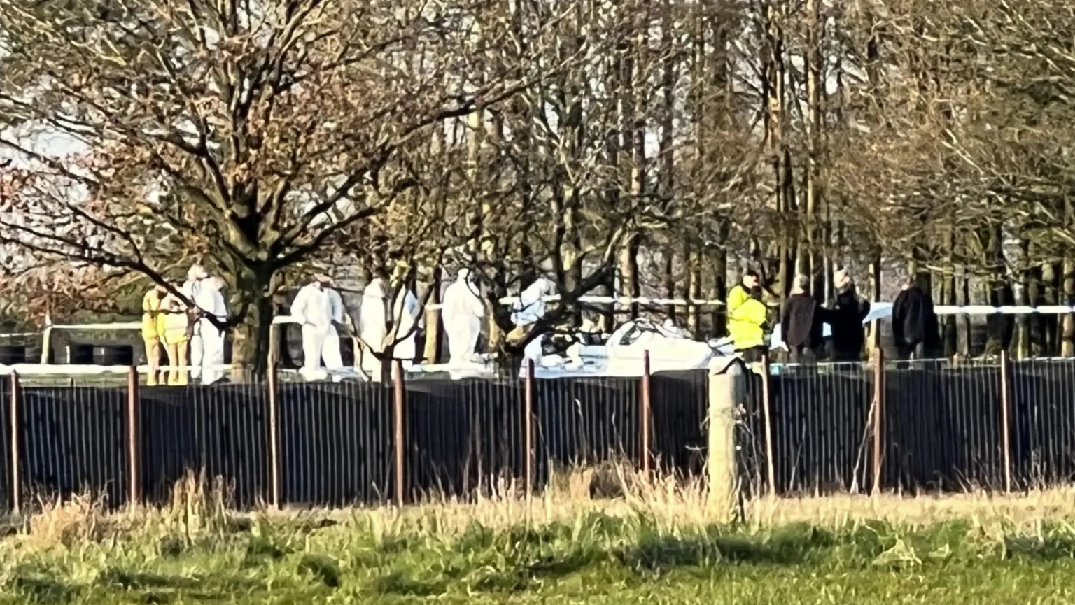 Lots of people in white forensic clothes surrounding a white plane