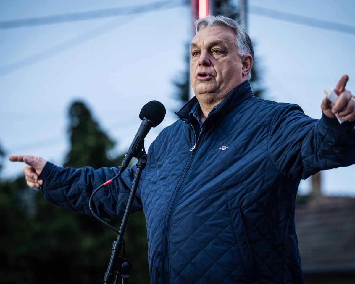 Viktor Orbán , speaking at a microphone onstage, arms outstretched and pointing
