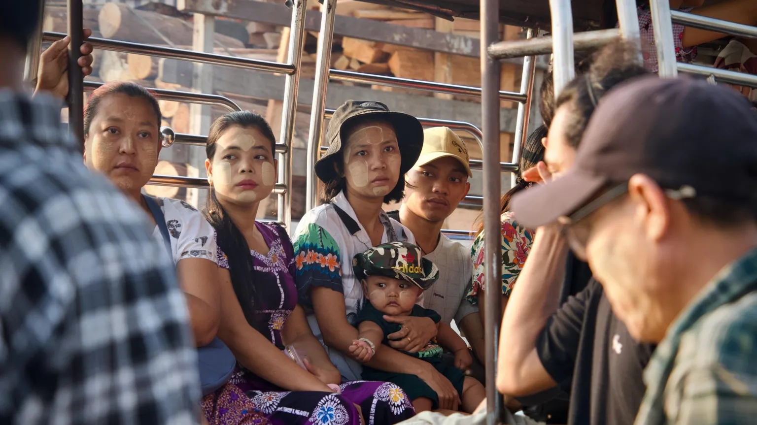 Lulu Luo/ BBC Three women, one holding a child in her lap, and a man seen on a bus in Yangon 