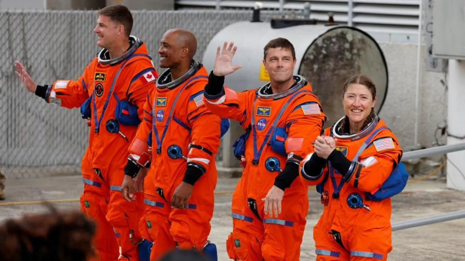  The four astronauts in their bright orange space suits waving before they get into the capsule.