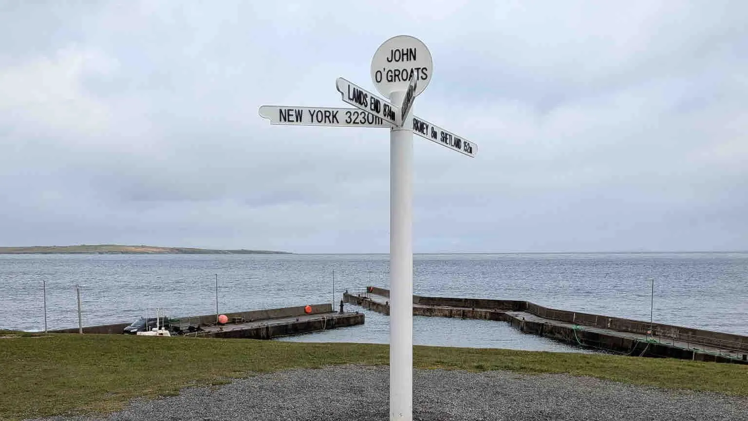 Barry Mackleston White sign reading 'John O Groats'. In the background is a large body of water.