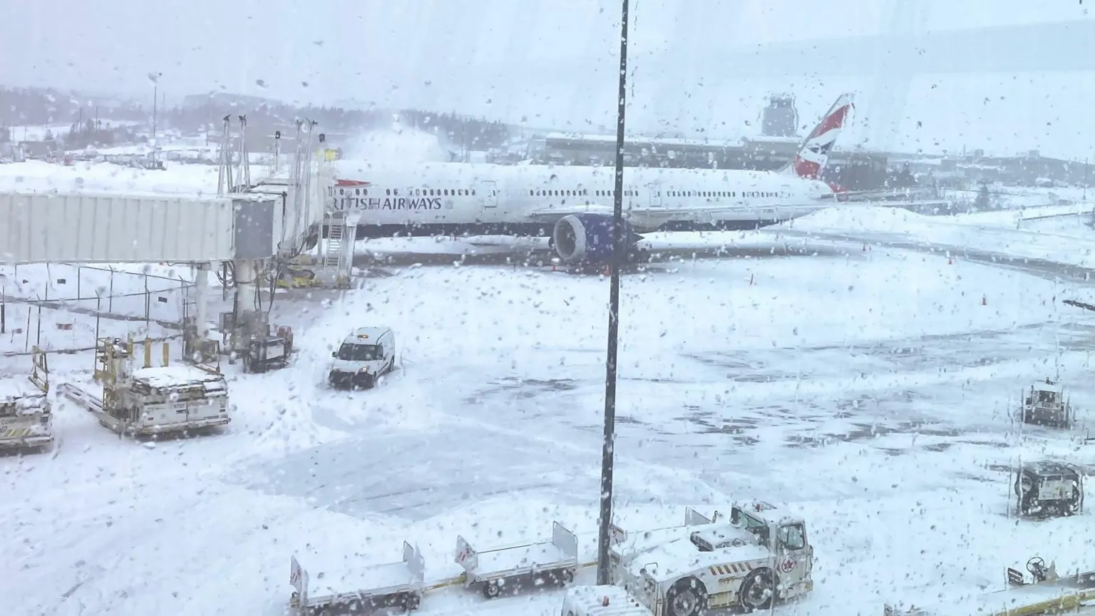 Jon Shipman Airside at a snow-covered airport, showing a runway covered in snow. A 'British Airways' plan can be seen in the distance. 
