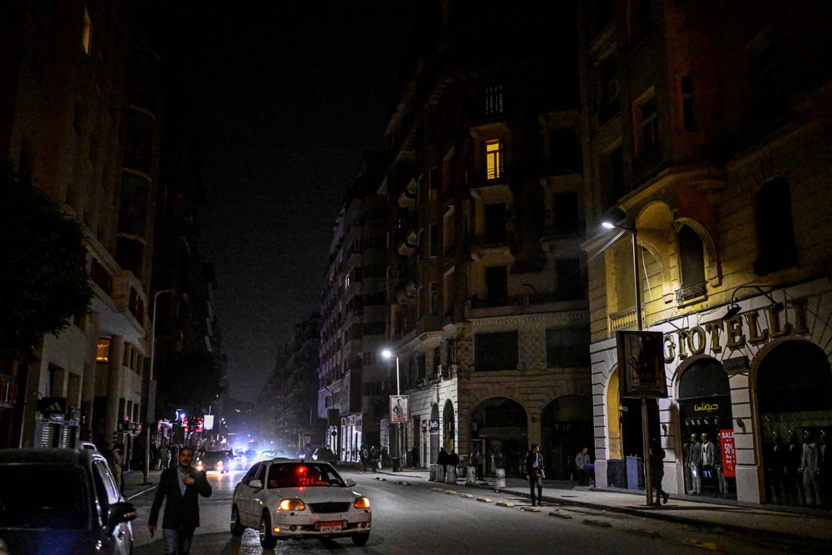 A car drives through a dark street in Cairo during the evening.