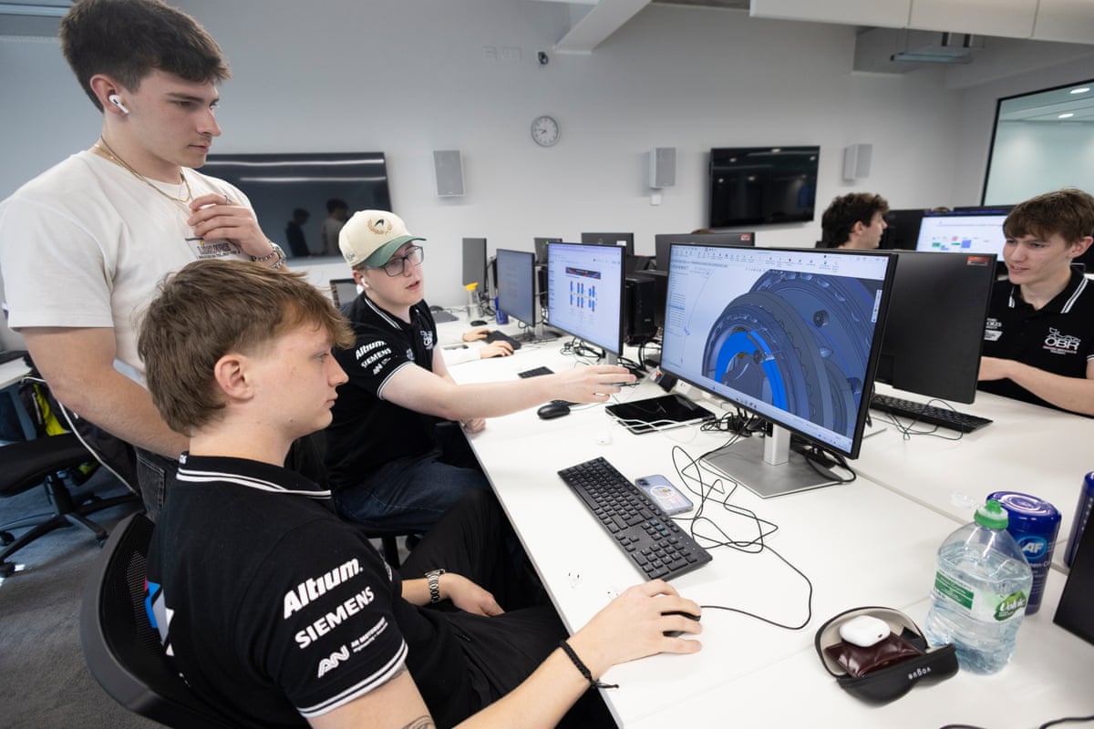 Three Oxford Brookes University students sit behind computer screens designing F1 cars