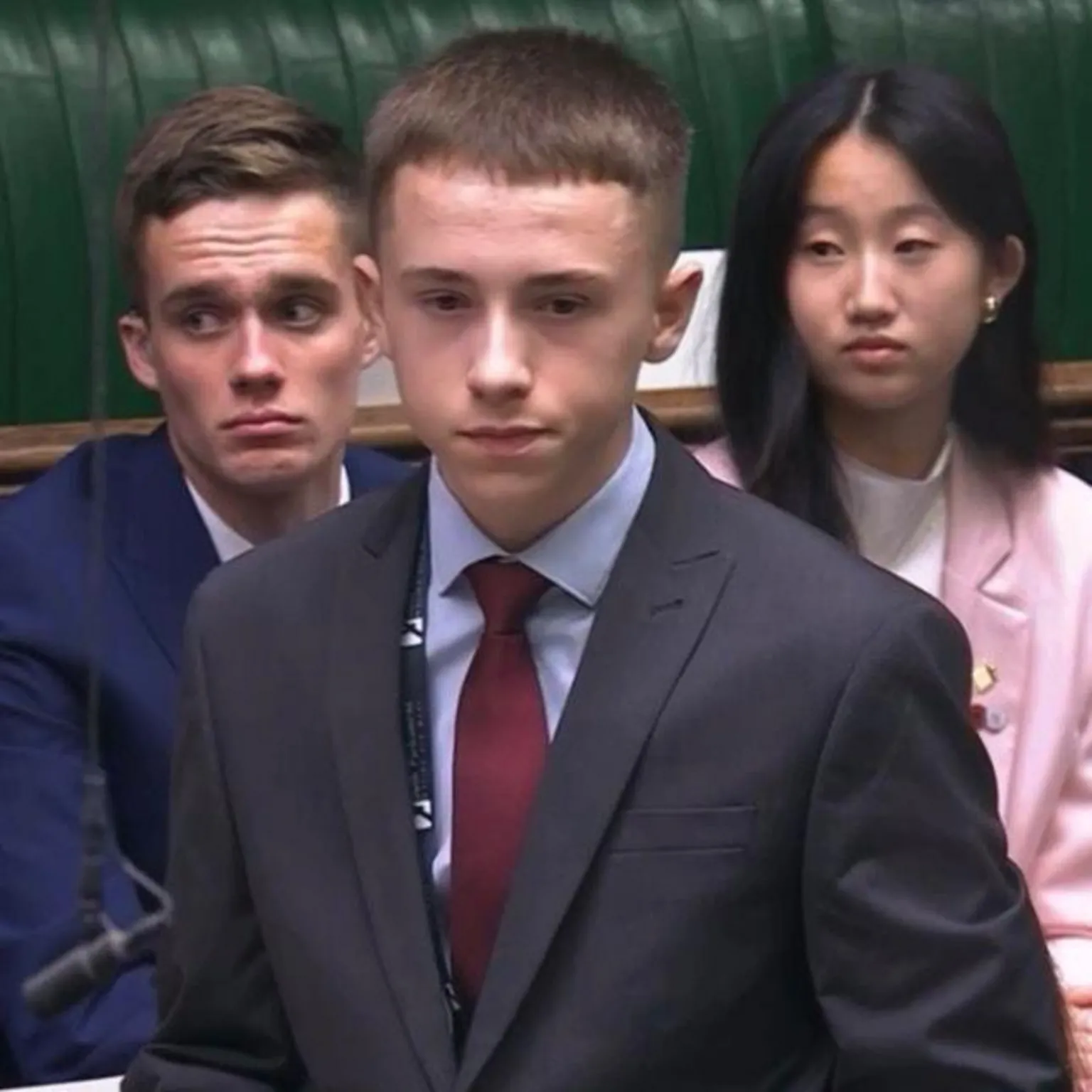 Secondary Students’ Union of Northern Ireland Three young people in formal attire. Kian Hawes, a boy with short hair, is standing at the front. A boy and girl are sat behind him.