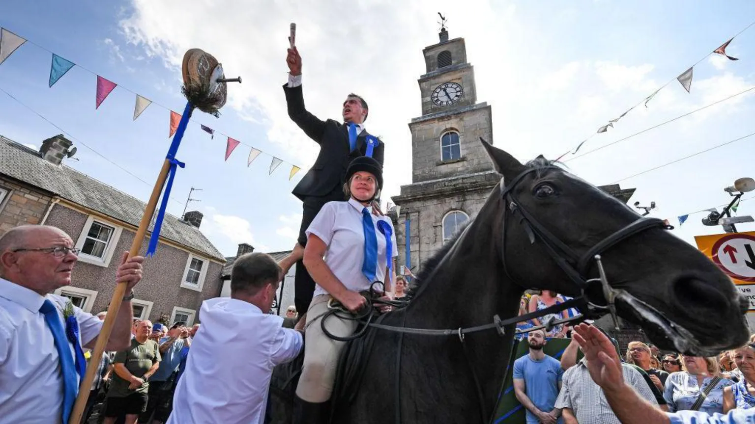  A man on horseback stands in front of the town clock in Langholm