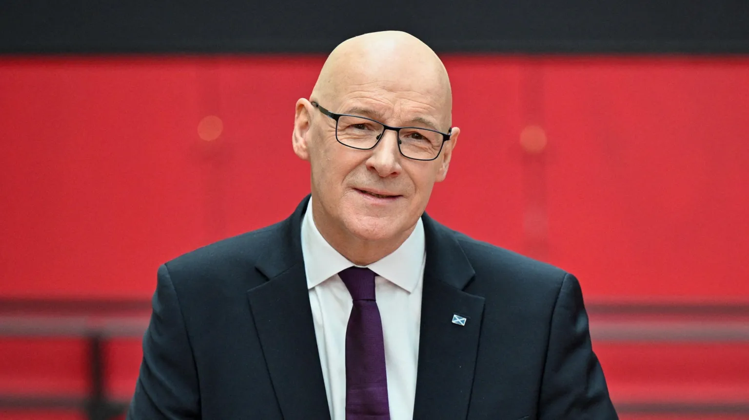  John Swinney smiling at the camera. He is wearing a suit. 