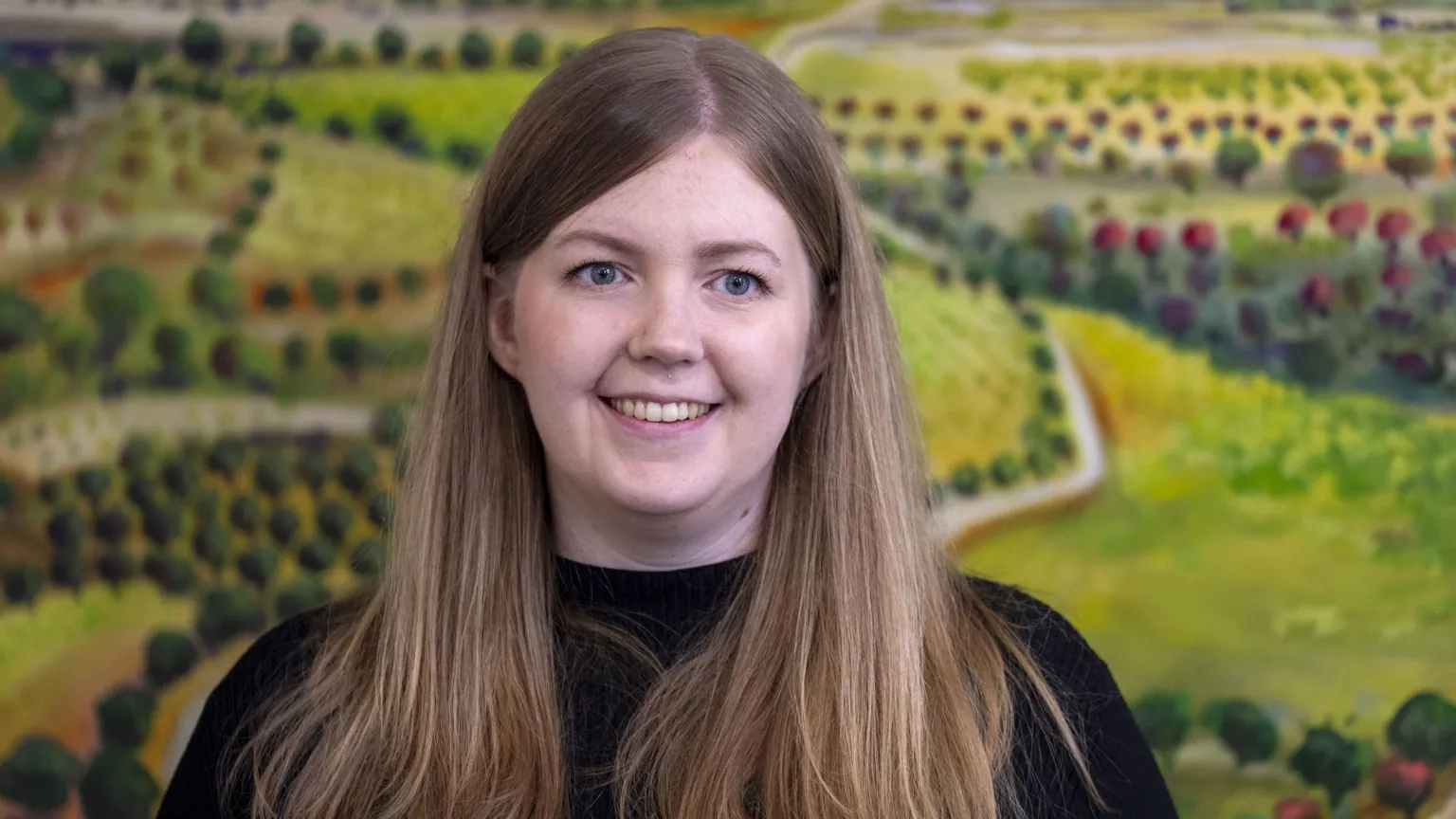  Gillian Mackay has long straight brown hair and is smiling at something out of frame 