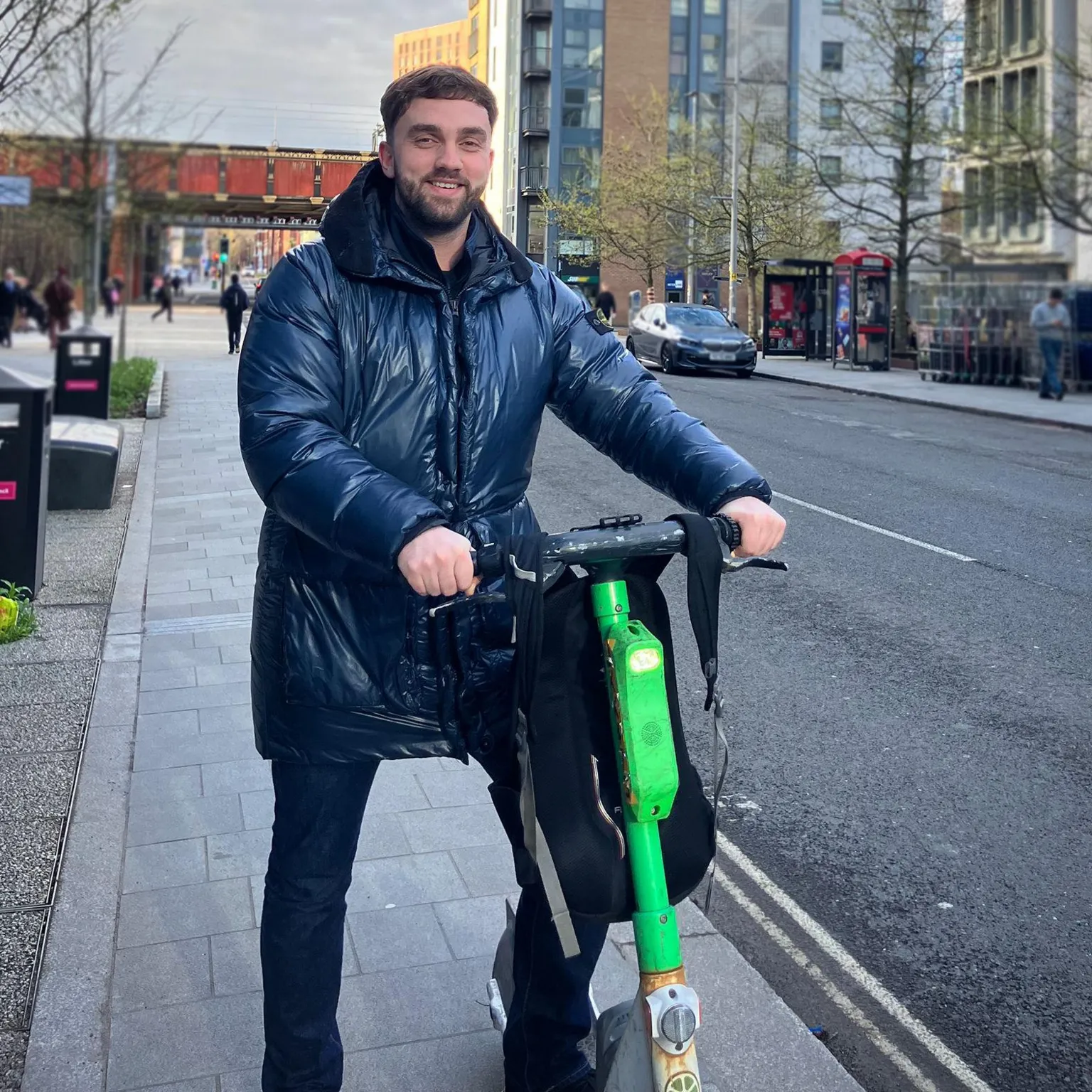 Jack stands on an e-bike on a pavement in Salford.