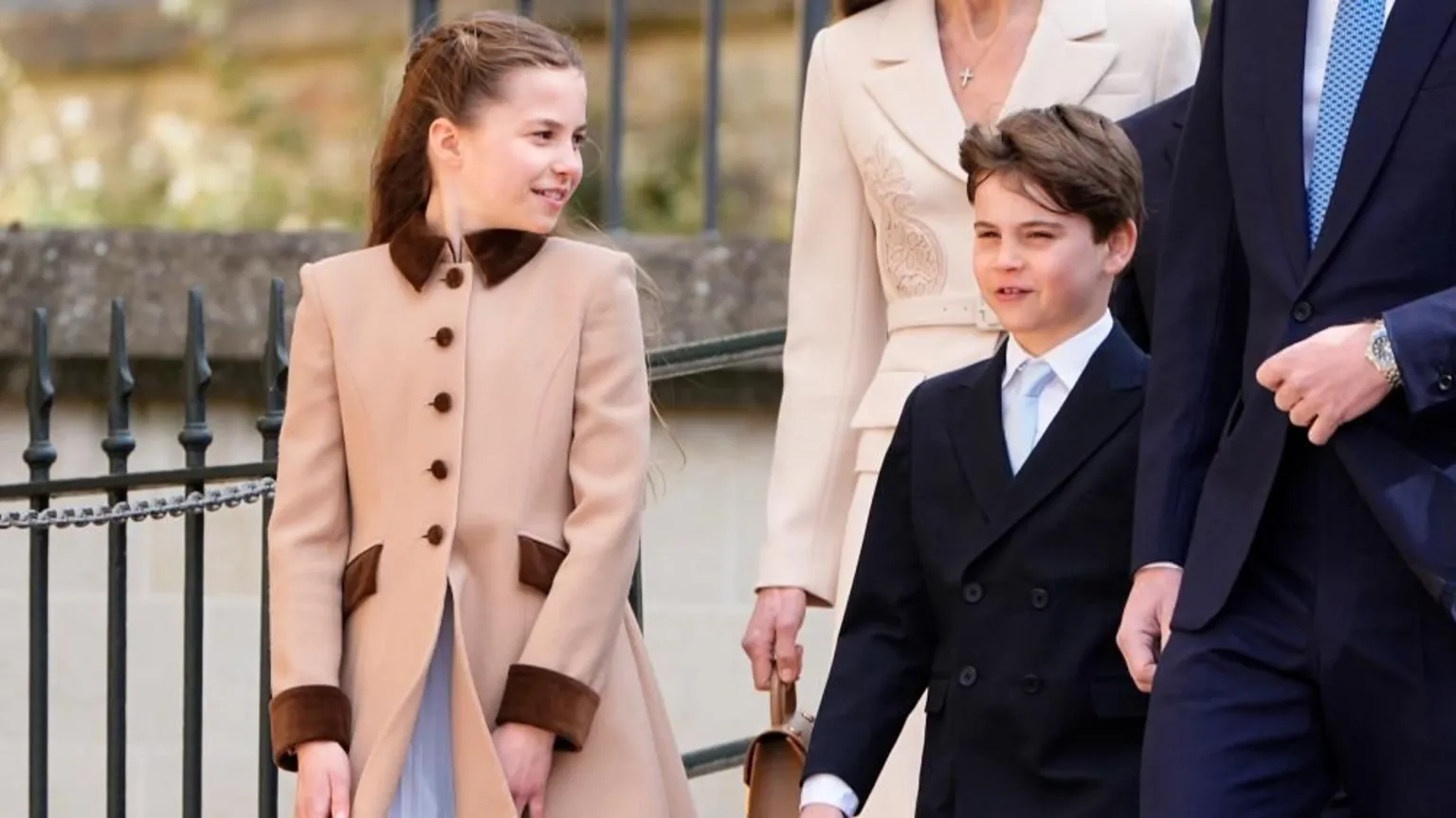  Princess Charlotte and Prince Louis walk and smile as Charlotte looks at her brother who looks ahead