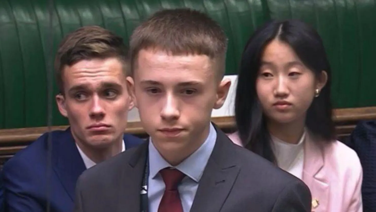 Secondary Students’ Union of Northern Ireland Three young people in formal attire. Kian Hawes, a boy with short hair, is standing at the front. A boy and girl are sat behind him.