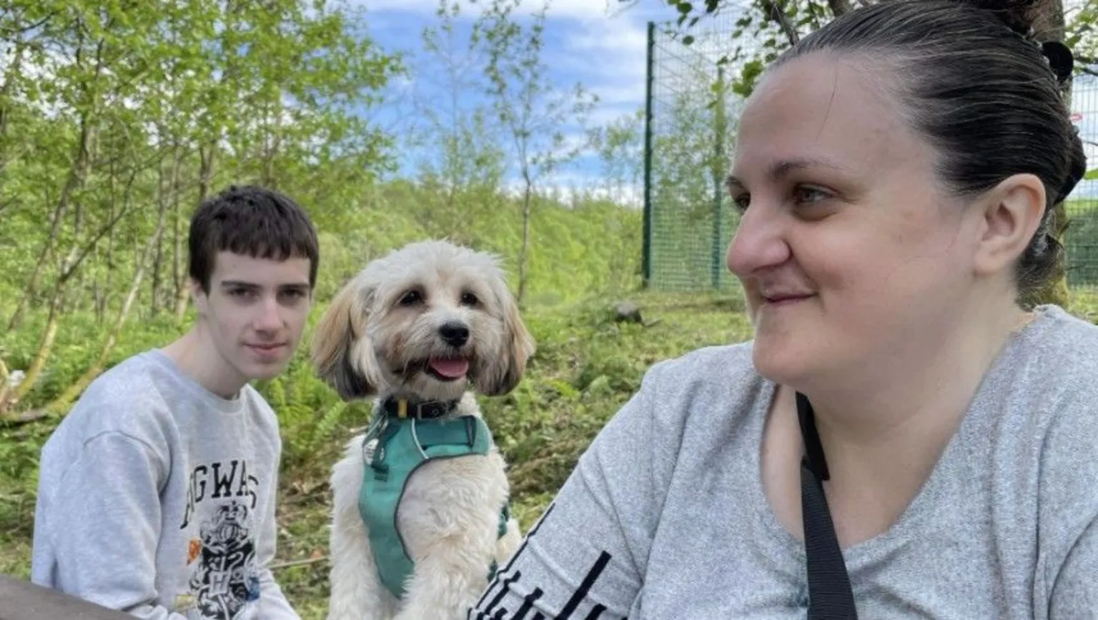 Erika Lye Logan, the family dog and mum, Erika sit on a park bench, with trees behind