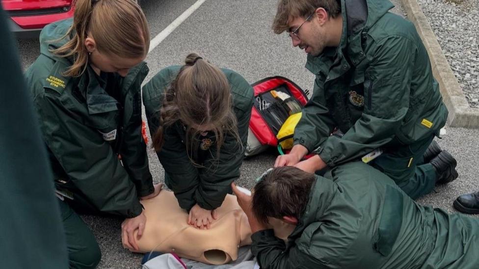 Myfyrwyr parafeddygol yn ymarfer delio gyda chlaf