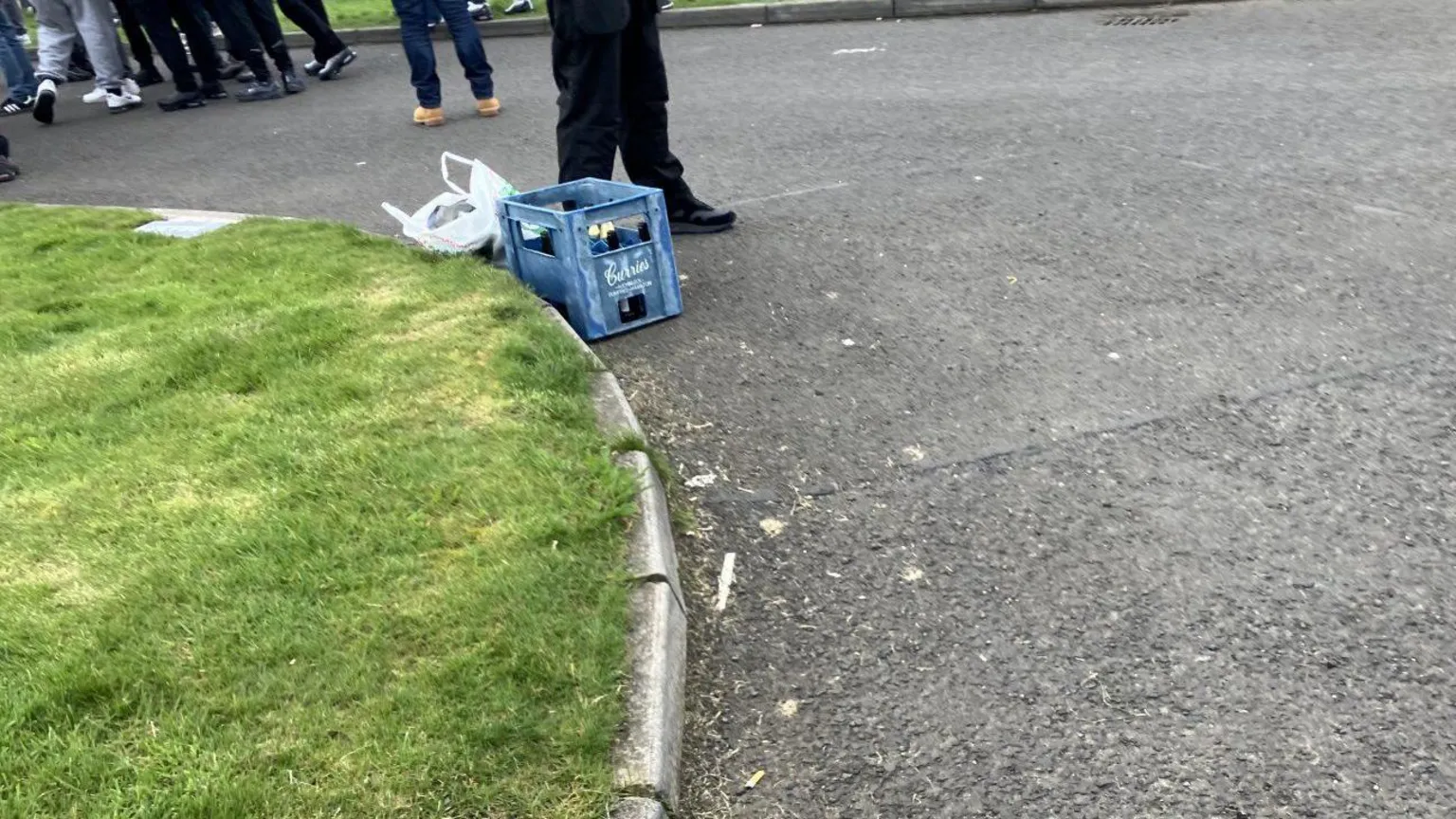 Shows a blue crate containing petrol bombs and the lower parts of people's bodies can be seen in the background