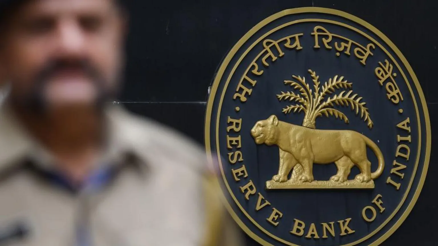 AFP via A security staff walks past the logo of Reserve Bank of India (RBI) at the RBI headquarters in Mumbai. 