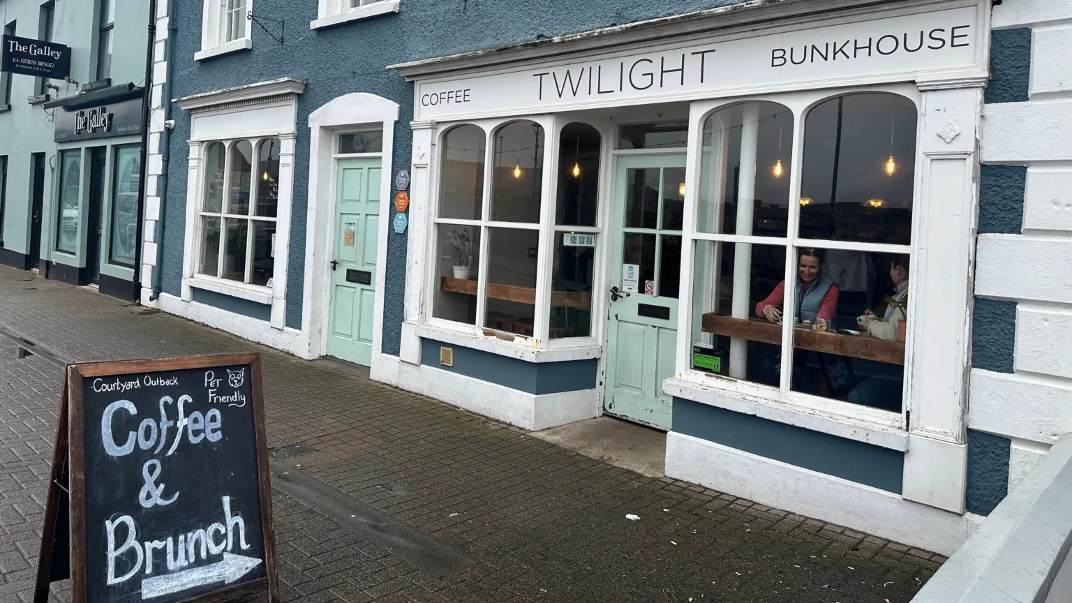 A shop front of a cafe with the name Twilight on the signage. There is a blackboard on the footpath in front of the cafe advertising coffee and brunch and also indicating that the cafe is pet friendly.