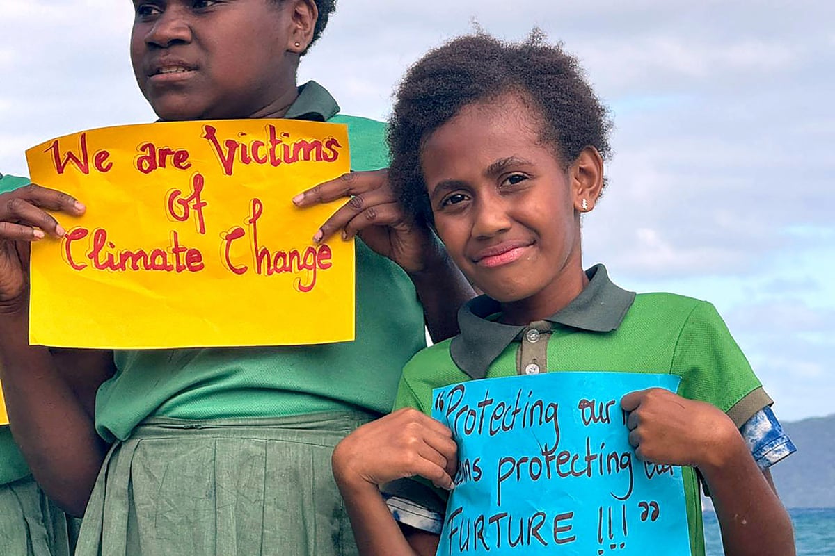 Children hold up signs, one saying ‘We are victims of climate change’