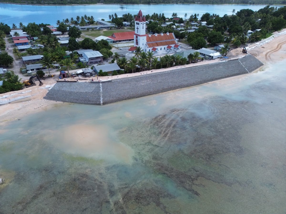 A sea wall in front of a church and houses