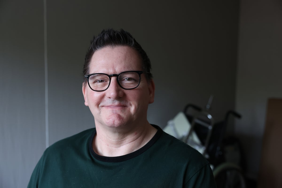 Richard Hewett wearing a dark-coloured T-shirt smiles at the camera