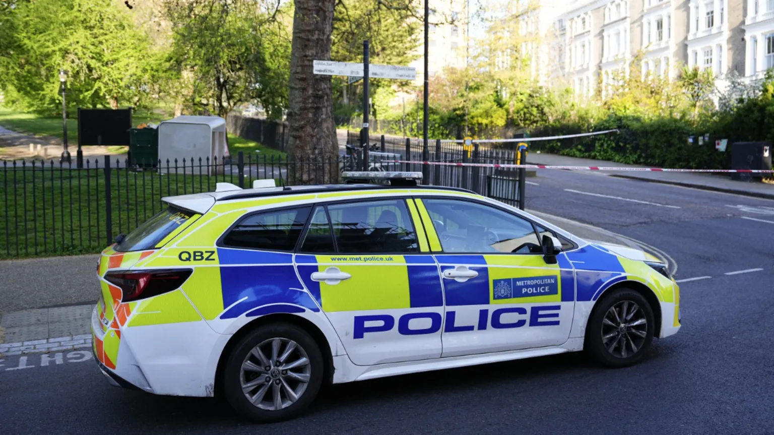 A police car parked at the edge of a police tape cordon.