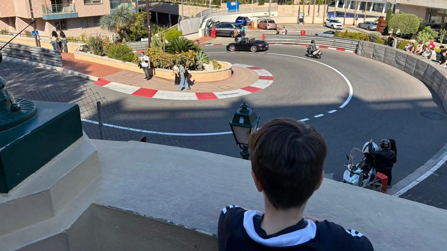 Rhona Paton the back of a young boys head, he is overlooking a hairpin bend in the road with high rise buildings surrounding it.