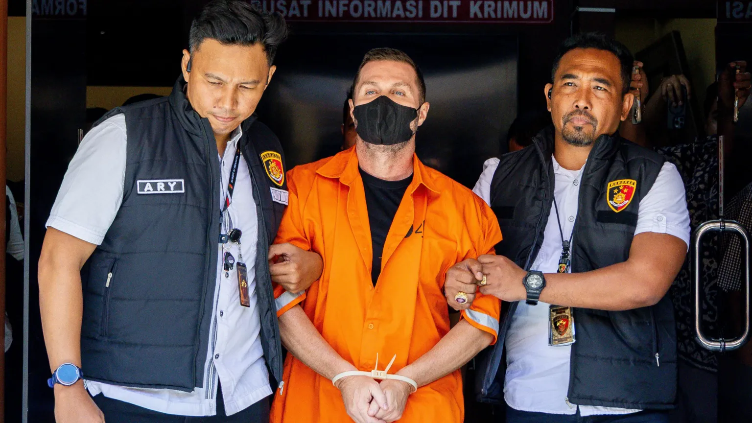 EPA Lyons has his hands tied together as he is led from the detention centre by two officers