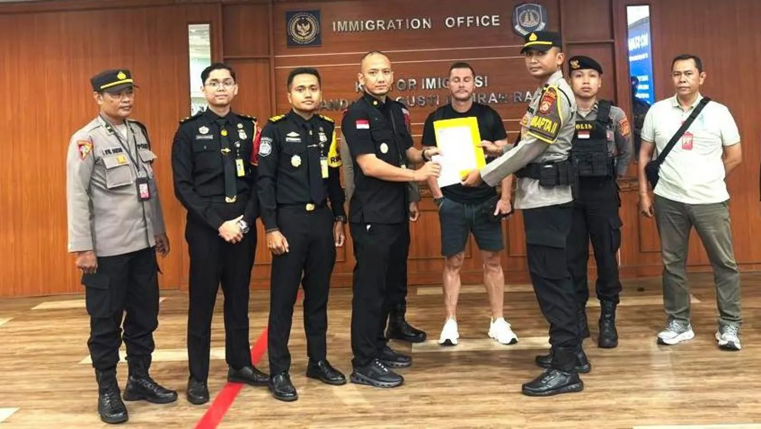 Ngurah Rai Immigration Office Steven Lyons flanked by police officers