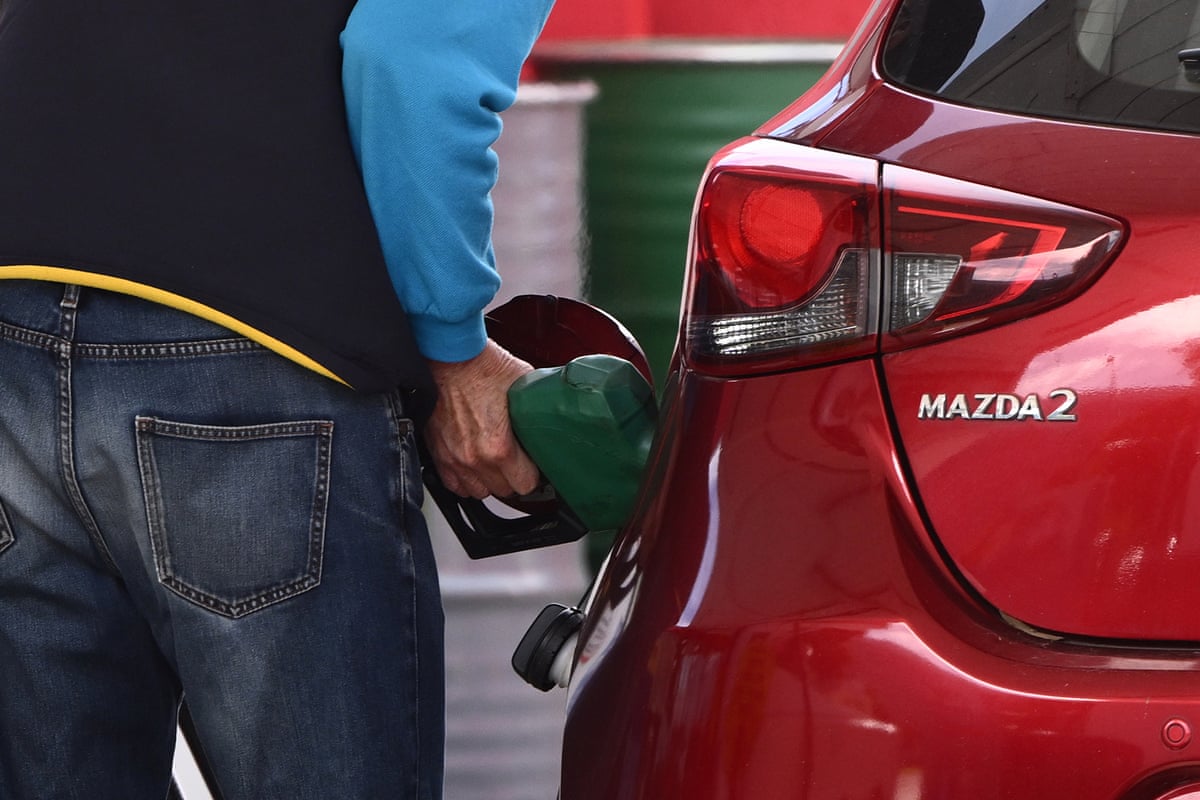 A person puts fuel into their vehicle