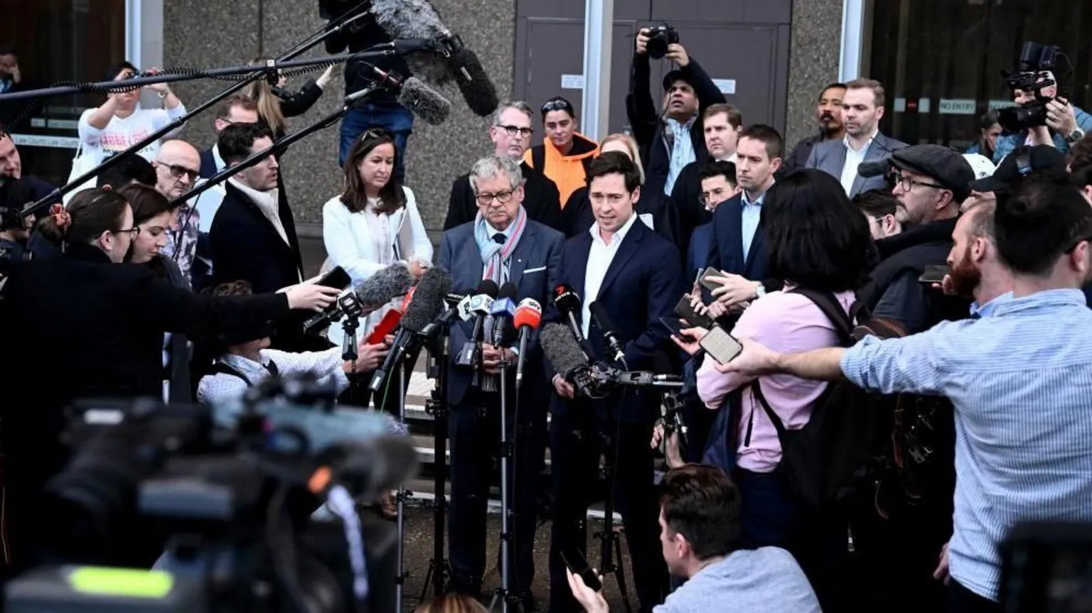  Journalists Nick McKenzie and Chris Masters give a statement outside the Federal Court, surrounded by a media pack