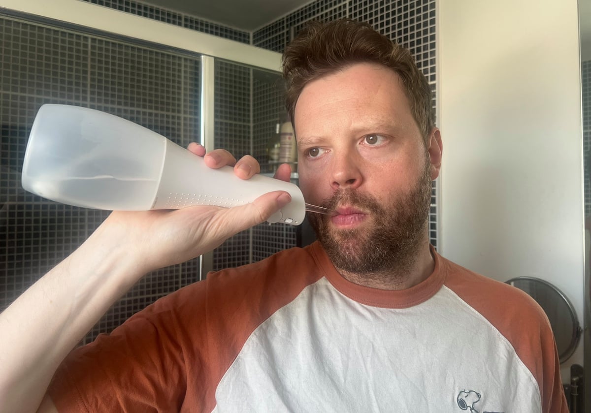 A man using a water flosser in his bathroom
