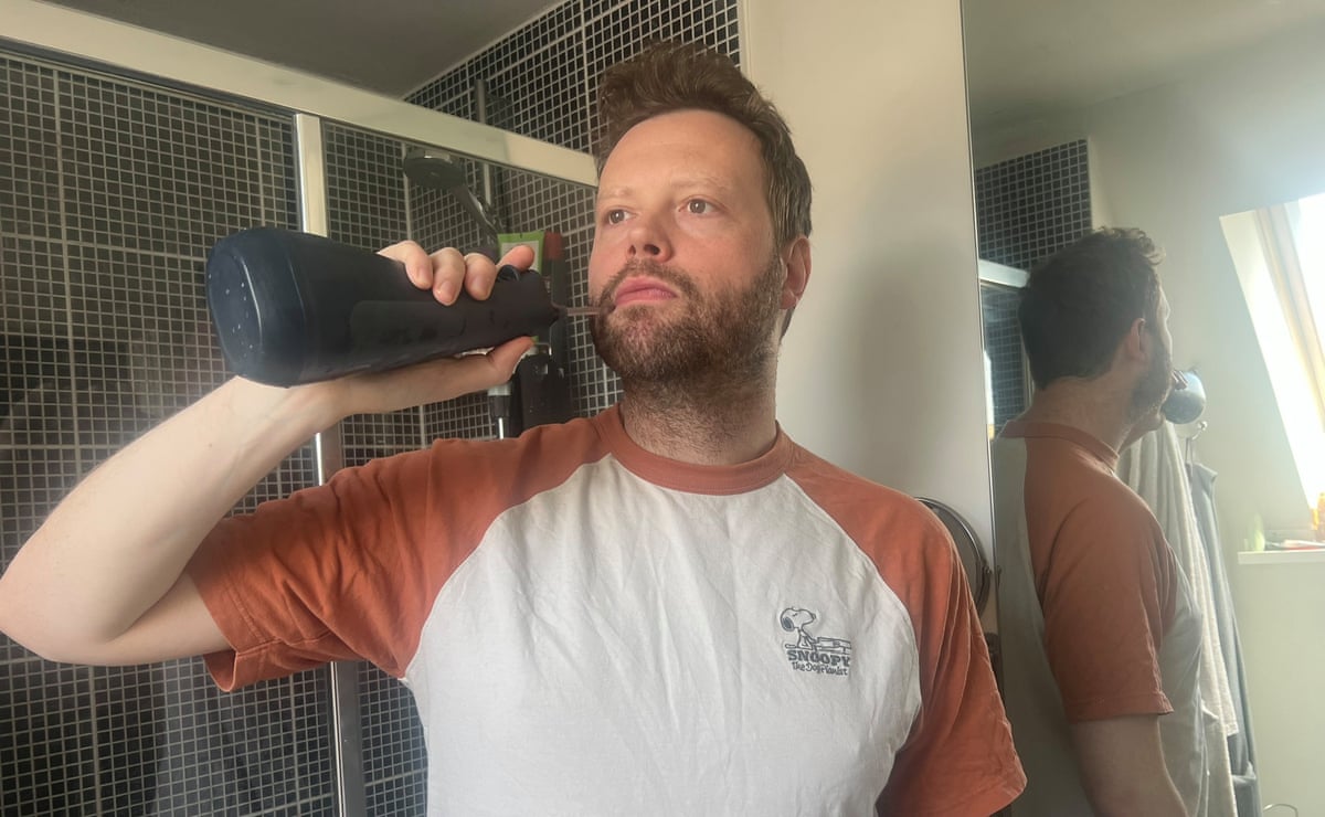 A man using a water flosser in his bathroom