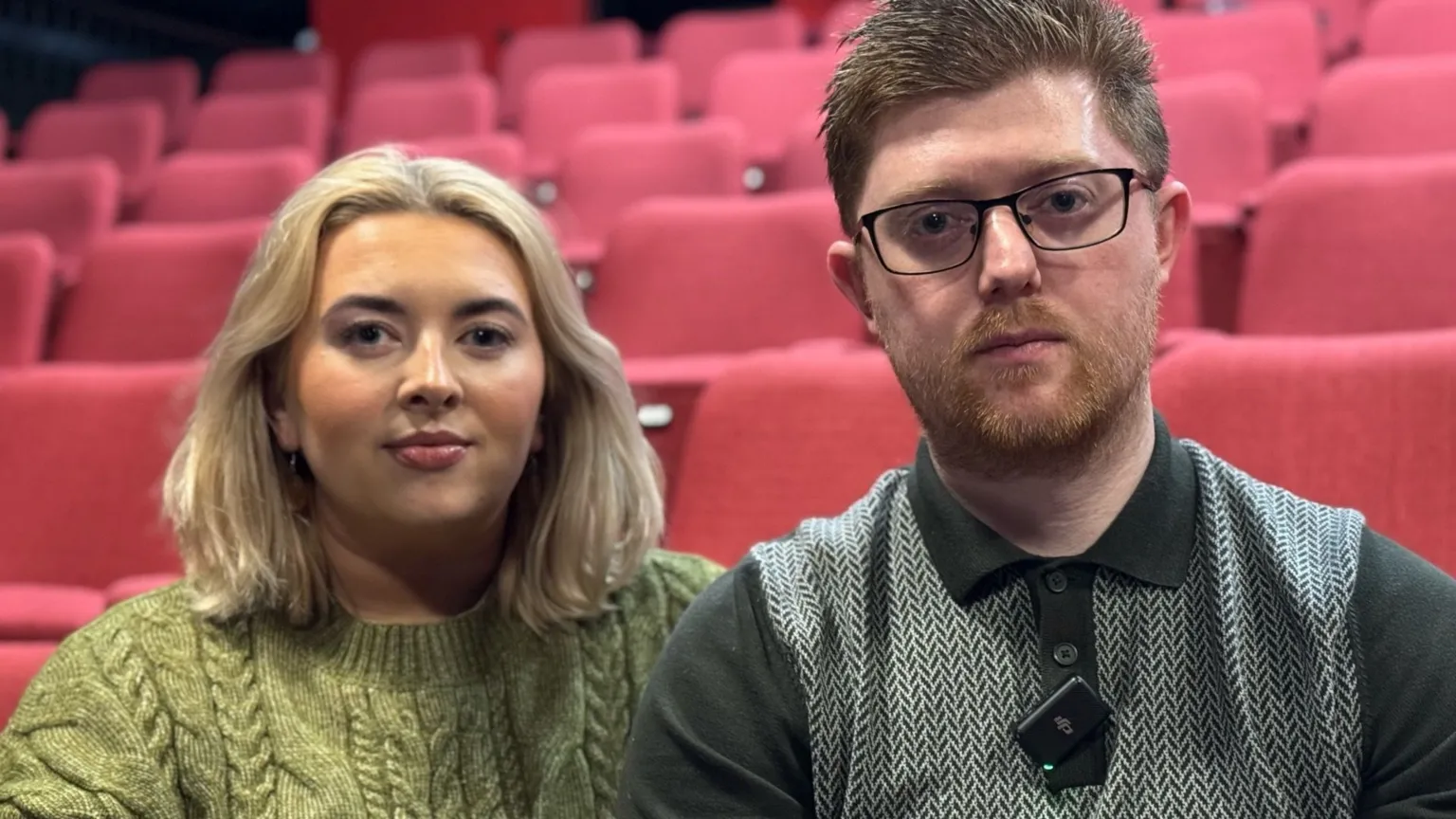 A woman with blonde hair and a green jumper and a man with brown hair and a black jumper.
