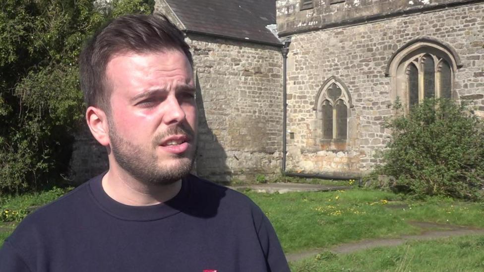 Y Cynghorydd Dewi Jones ger Eglwys Llanbeblig, Caernarfon