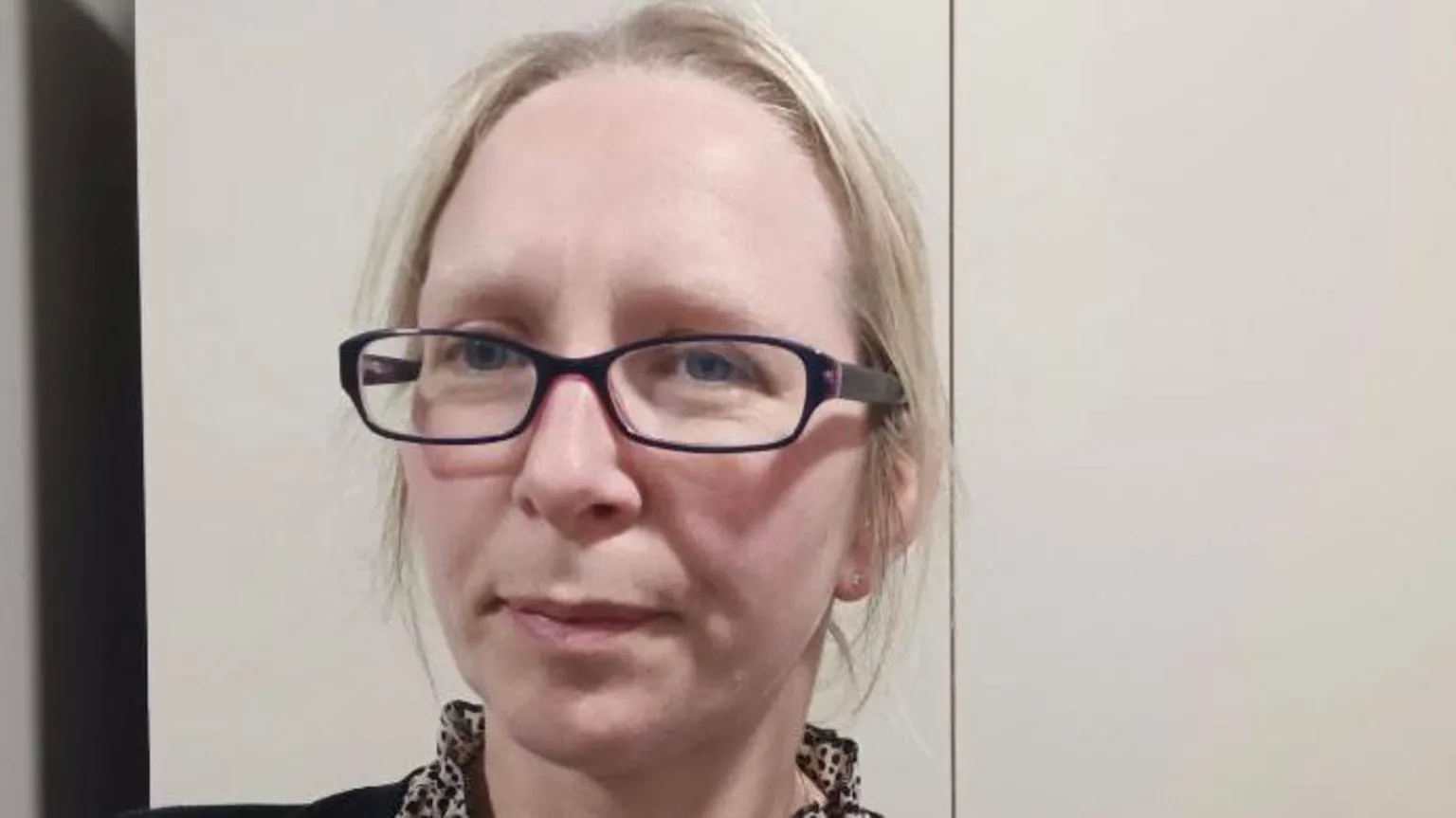 Handout Karen has taken a selfie. She has blond hair and is wearing glasses. She is standing in front of a white wall.