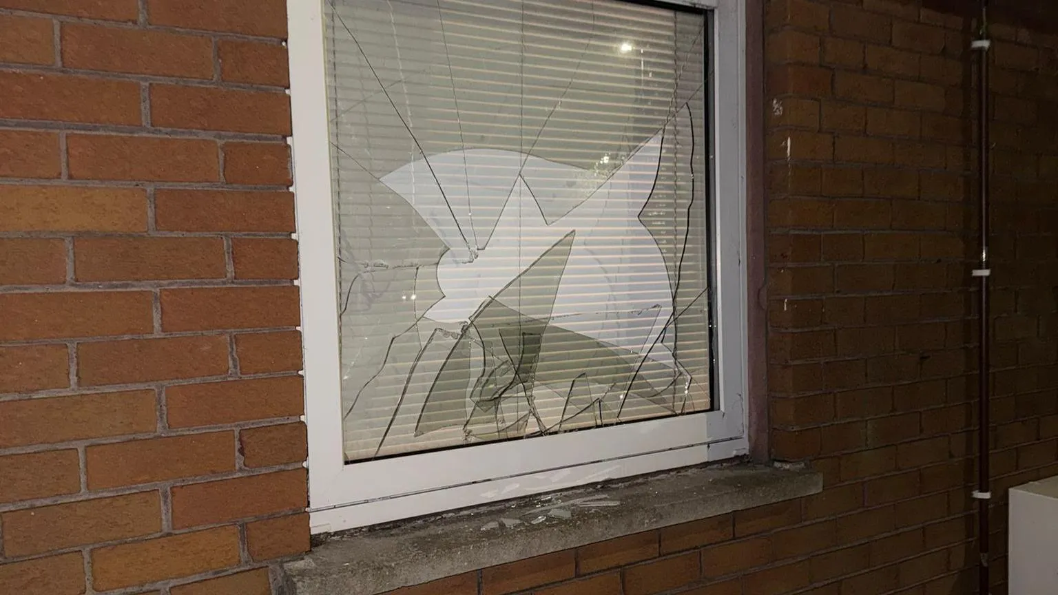 Handout A small window with smashed glass on a bricked house 