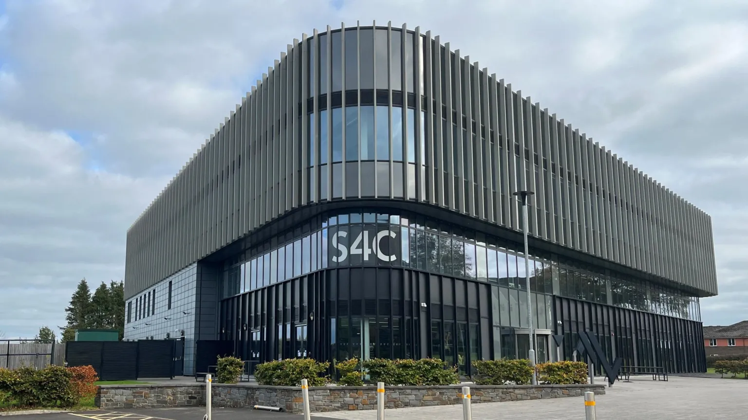 The exterior of the S4C building. It is black panelled with vertical windows and the word S4C in white font. 