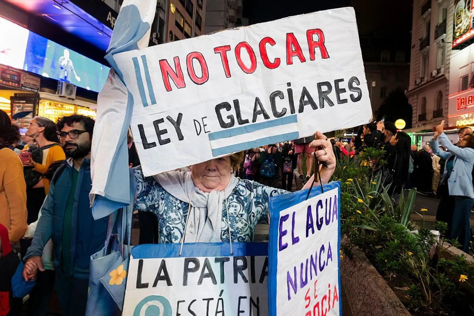  An eldery lady holds a sign which says in Spanish 'Don't touch the glacier law'