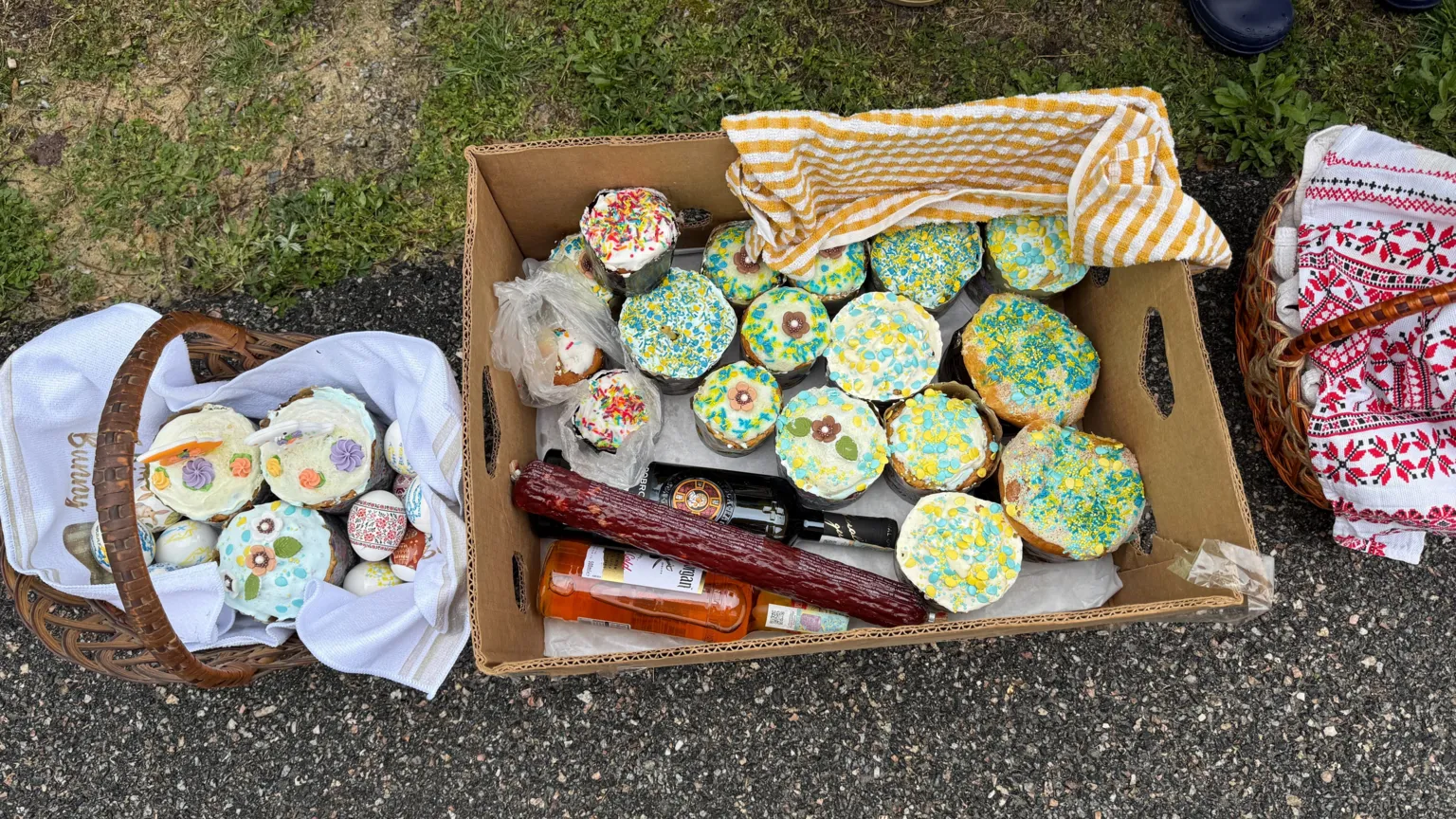 Baskets full of iced Easter cakes, painted eggs and sausage.