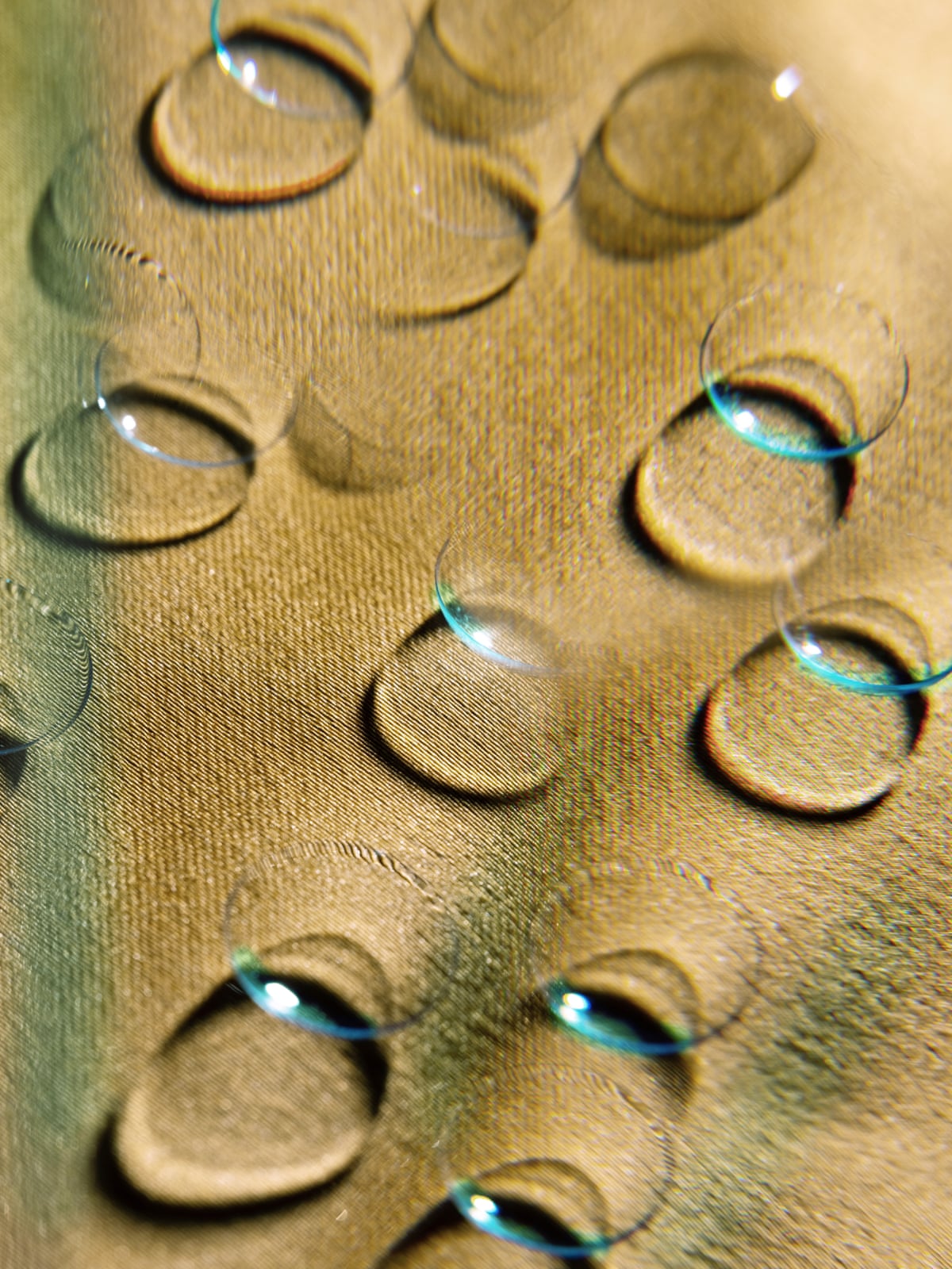 Contact lenses are arranged and reflect on a textured, golden-brown fabric surface.