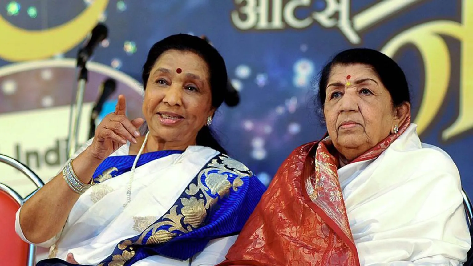 AFP Indian Hindi and Marathi language Bollywood playback singer Lata Mangeshkar (R) speaks with her sister Asha Bhosle also a playback singer during the Pandit Hridaynath Mangeshkar’ Awards in Mumbai late March 31, 2013. AFP PHOTO/STR (Photo credit should read STRDEL/AFP via )