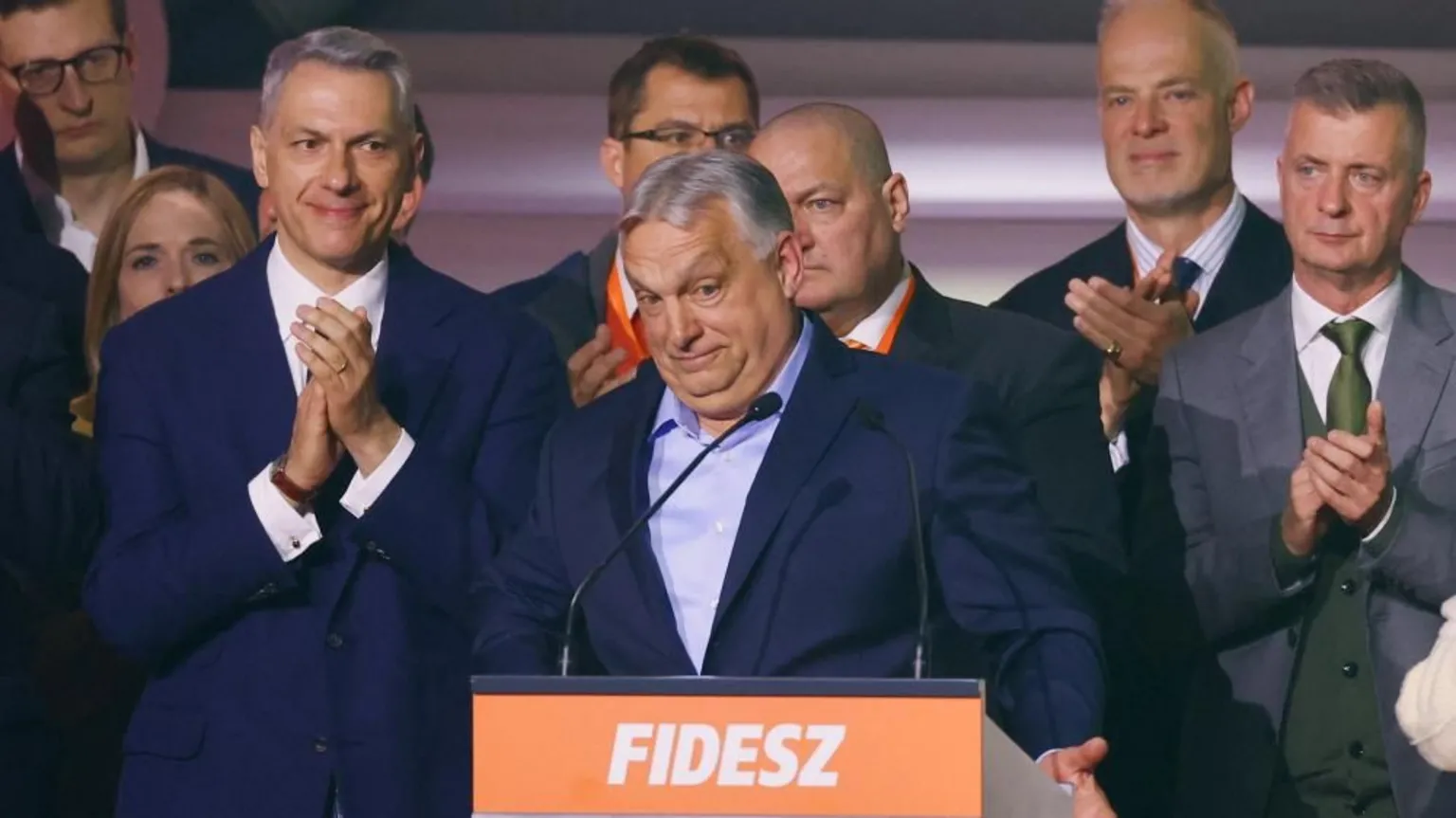 AFP via A man in a suit stands surrounded by other men