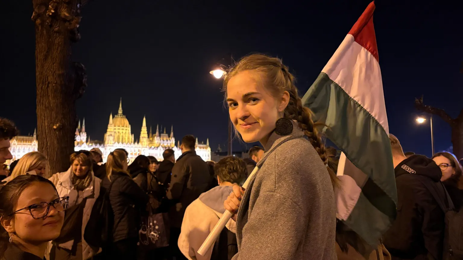 A young woman with long plaited hair holds a Hungary flag at celebrations opposite the national parliament at the River Danube.