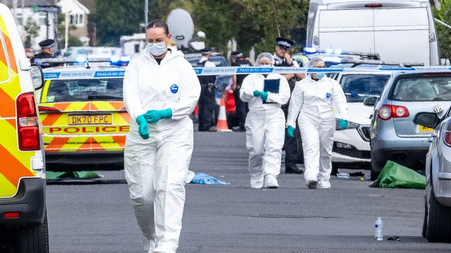  Police scenes-of-crime officers at the scene in Southport where three girls were fatally stabbed at a dance class. They are wearing full-length white scrubs, blue plastic gloves and face masks. 
