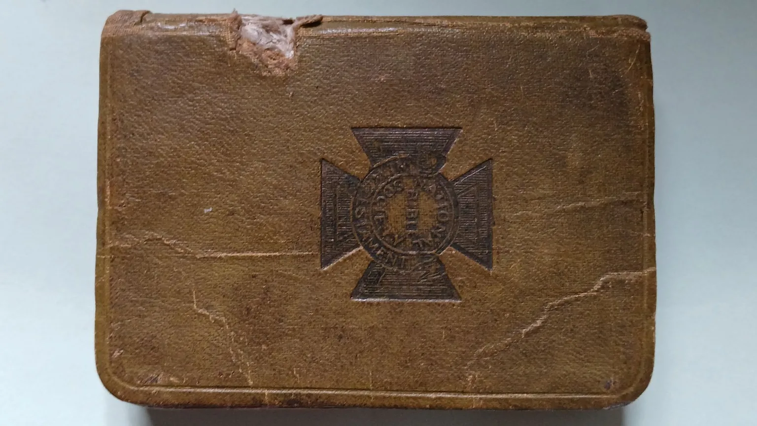 Macfarlane family A brown leather bible with a military cross emblem on the front cover. On the left hand side of the bible, close to the spine, the leather has been broken with some white material seen beneath