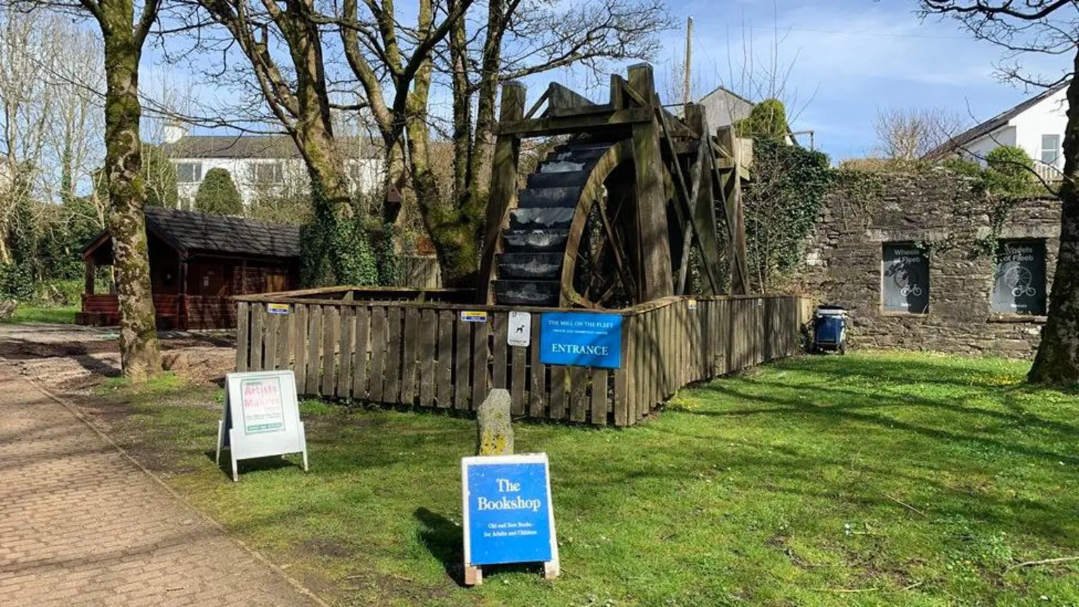 A bookshop on a green with signs outside.