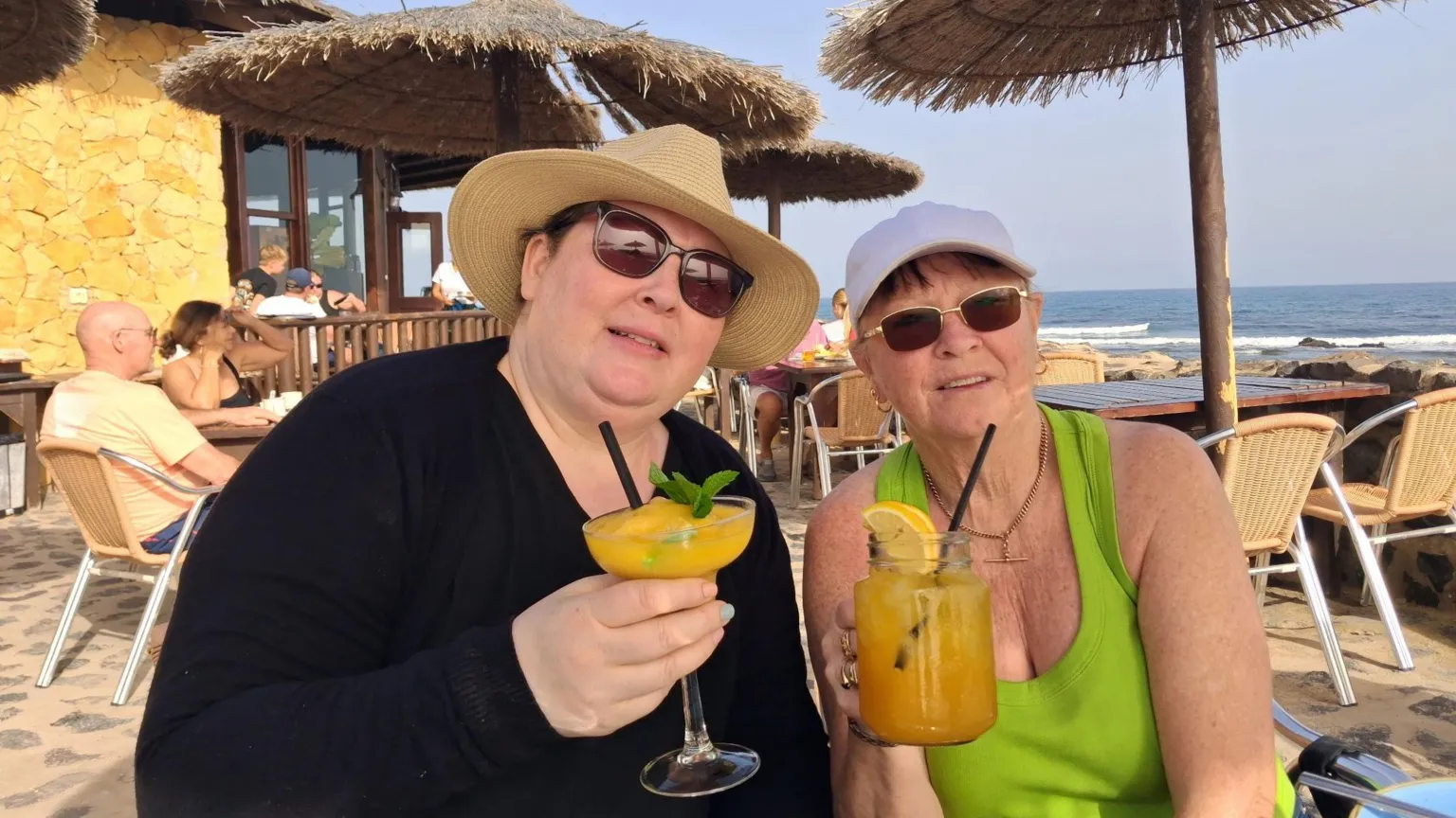 Delia Lodge Rebecca is on the left and Delia is on the right. The pair are pictured on a beach drinking a cocktail each.