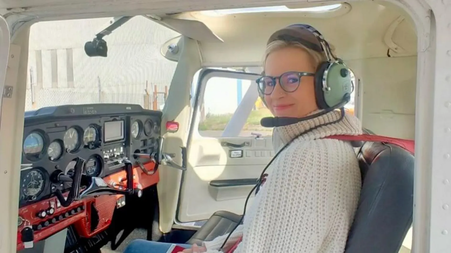Christina Mackaill Christina Mackaill in a simulation aircraft. She is wearing glasses, a cream wool jumper and headset.
