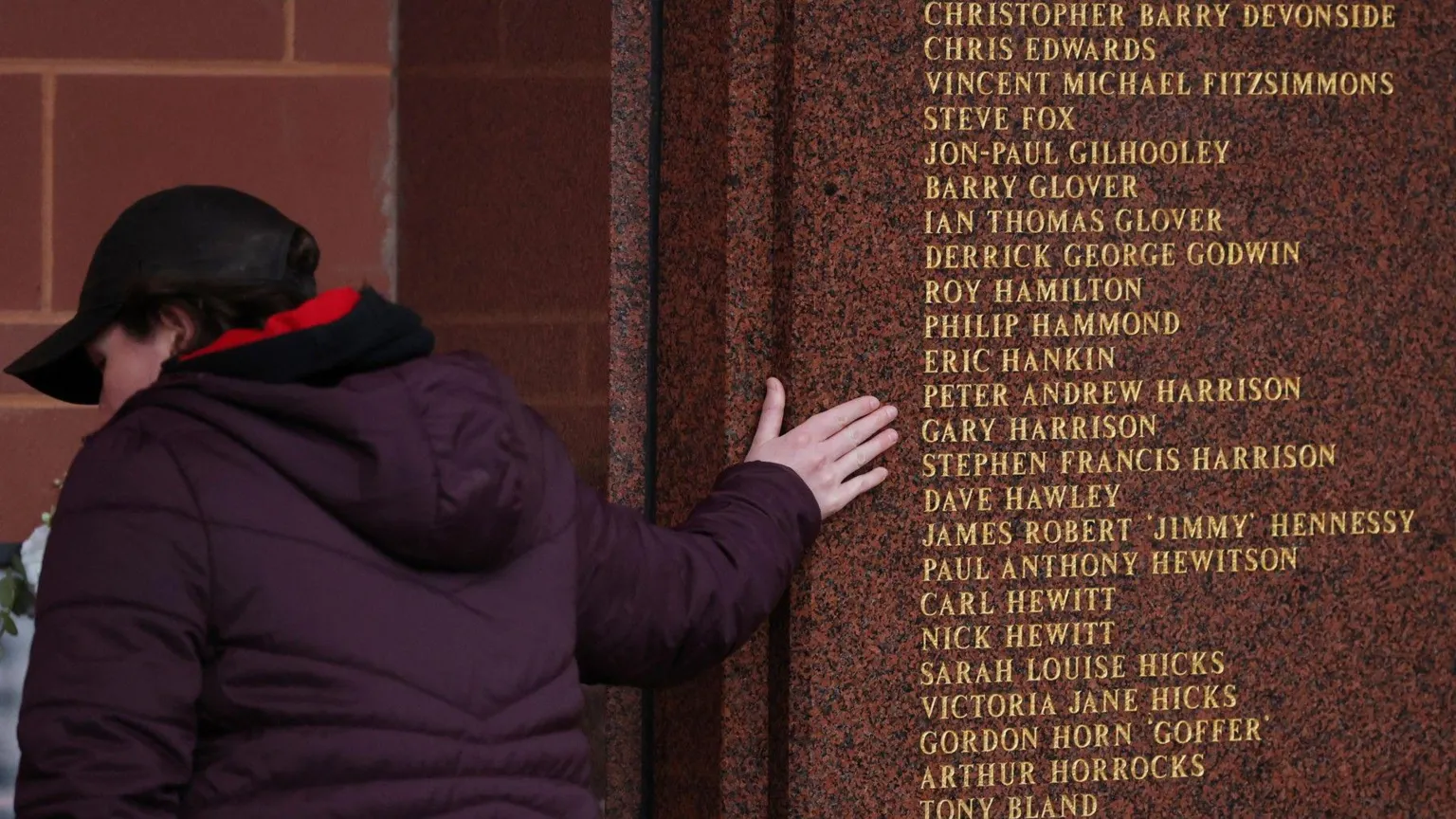  A Liverpool fan touches the Hillsborough Memorial at Anfield stadium which lists the names of those who died