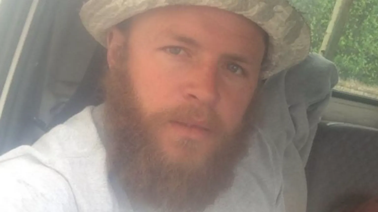 Facebook Kirk Bishop - a man with a full, reddish-brown beard and moustache, wearing a grey T-shirt and light camoflauge brimmed hat. He is looking directly at the camera with his blue eyes.
